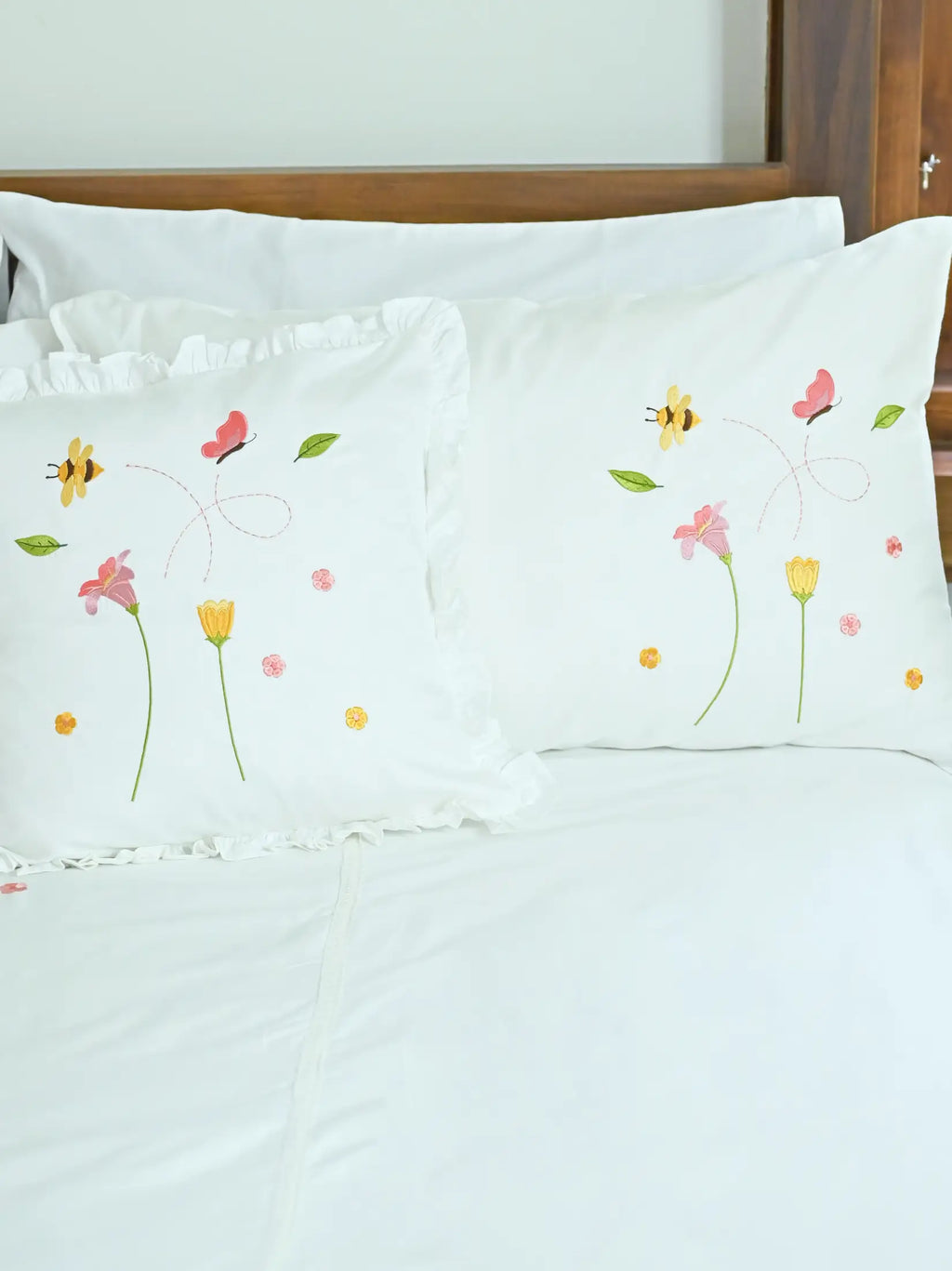 Two white Bees and Blossom embroidered pillowcases, one plain edged and one ruffled
