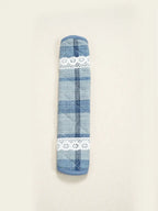 Close-up of a blue plaid fabric handle cover with white lace trim