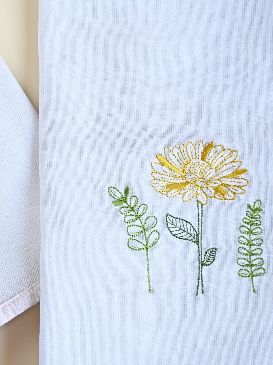 Close-up of yellow flower and green leaf embroidery on a white Kerala bath towel