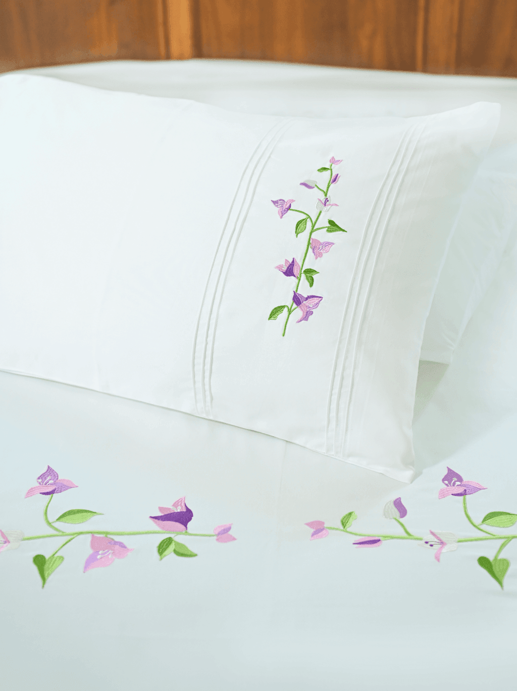 White pillowcase and bed sheet with pink and purple bougainvillea embroidery