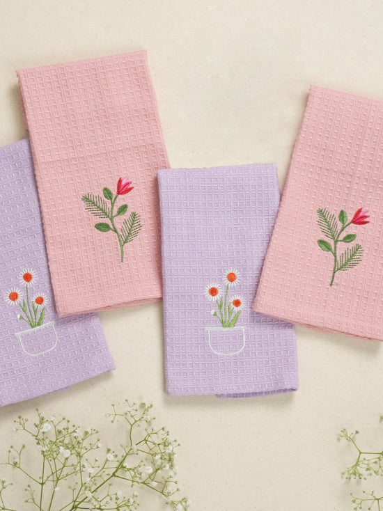 Four pink and lavender waffle face towels embroidered with red tulips and orange daisies