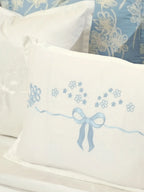 Close-up of a pale blue embroidered bow and flowers on a white cushion cover