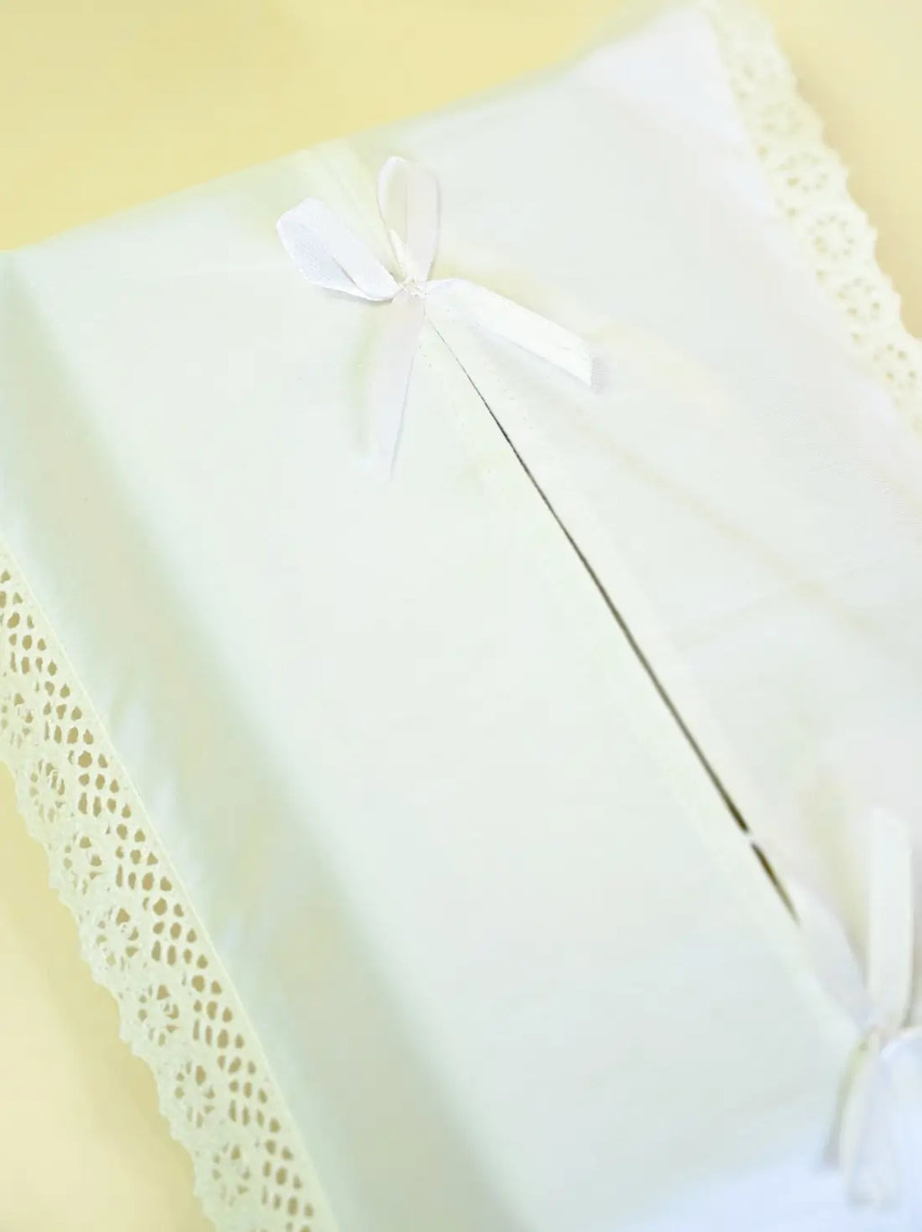 Close-up of a white ribbon bow and lace trim on a tissue box cover
