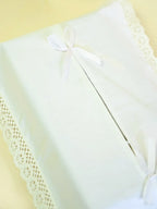 Close-up of a white ribbon bow and lace trim on a tissue box cover