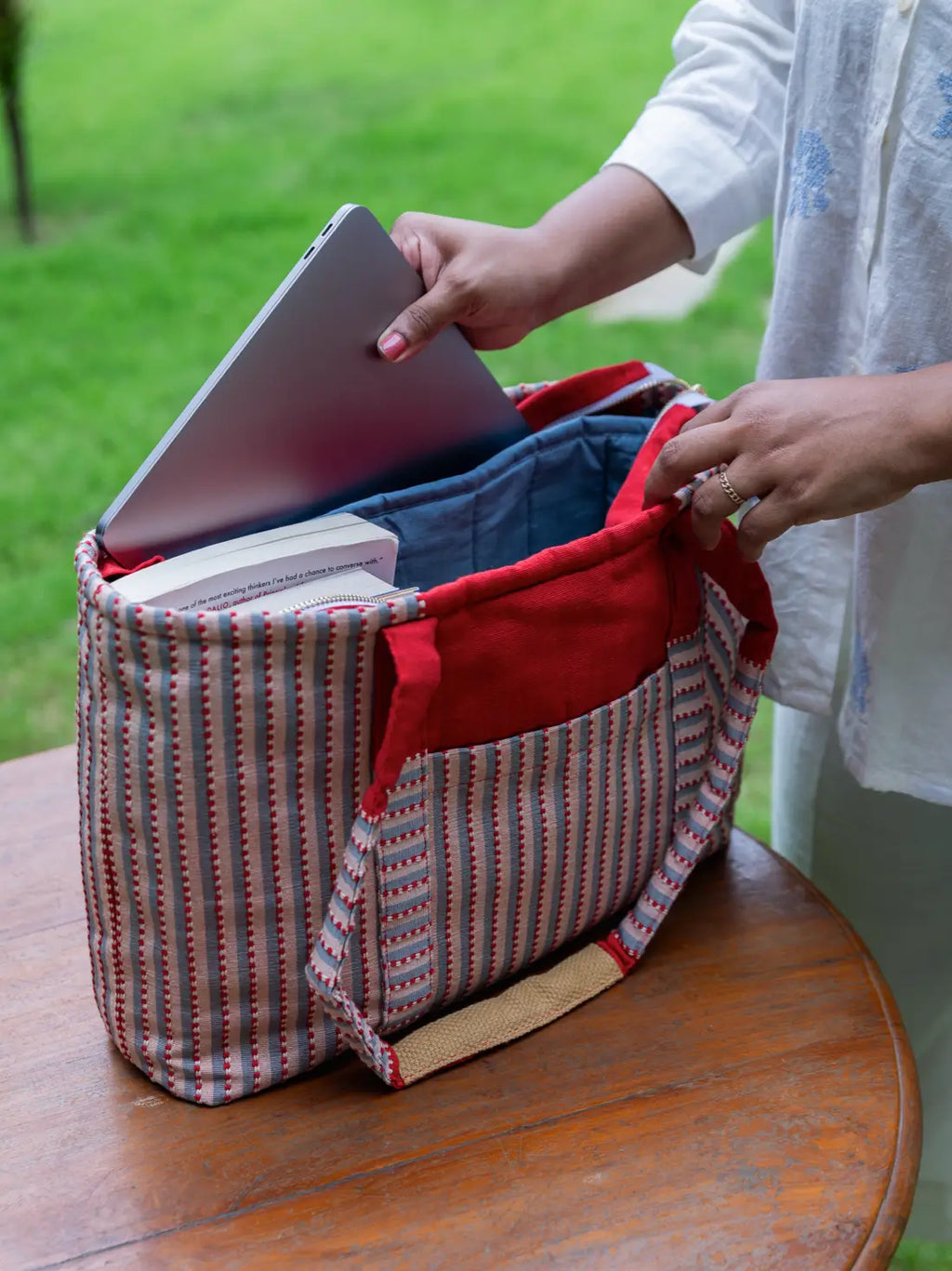 Open striped tote showing a padded laptop compartment, inner pocket and book