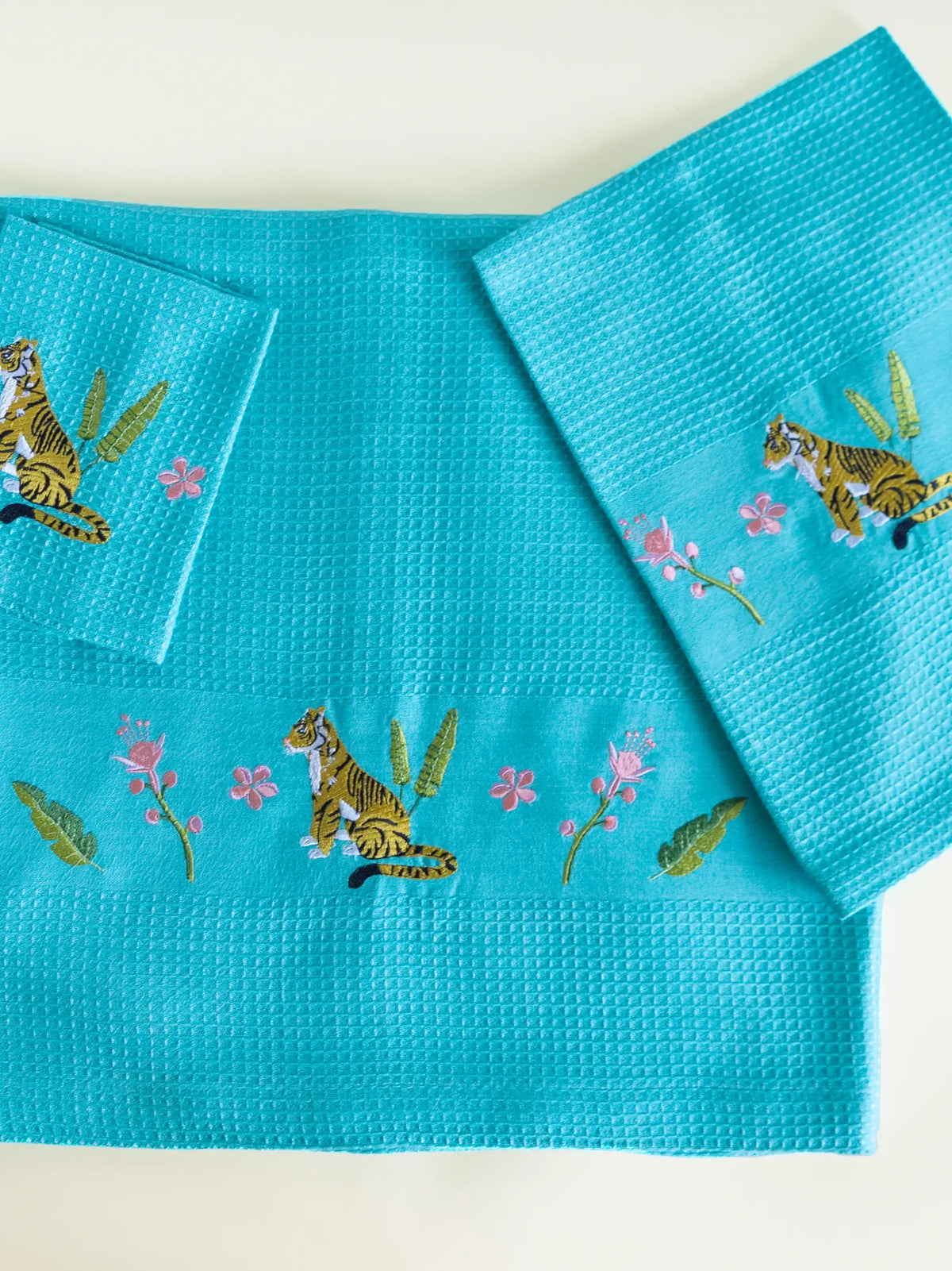 Teal blue waffle bath, hand and face towels with tiger and pink floral embroidery