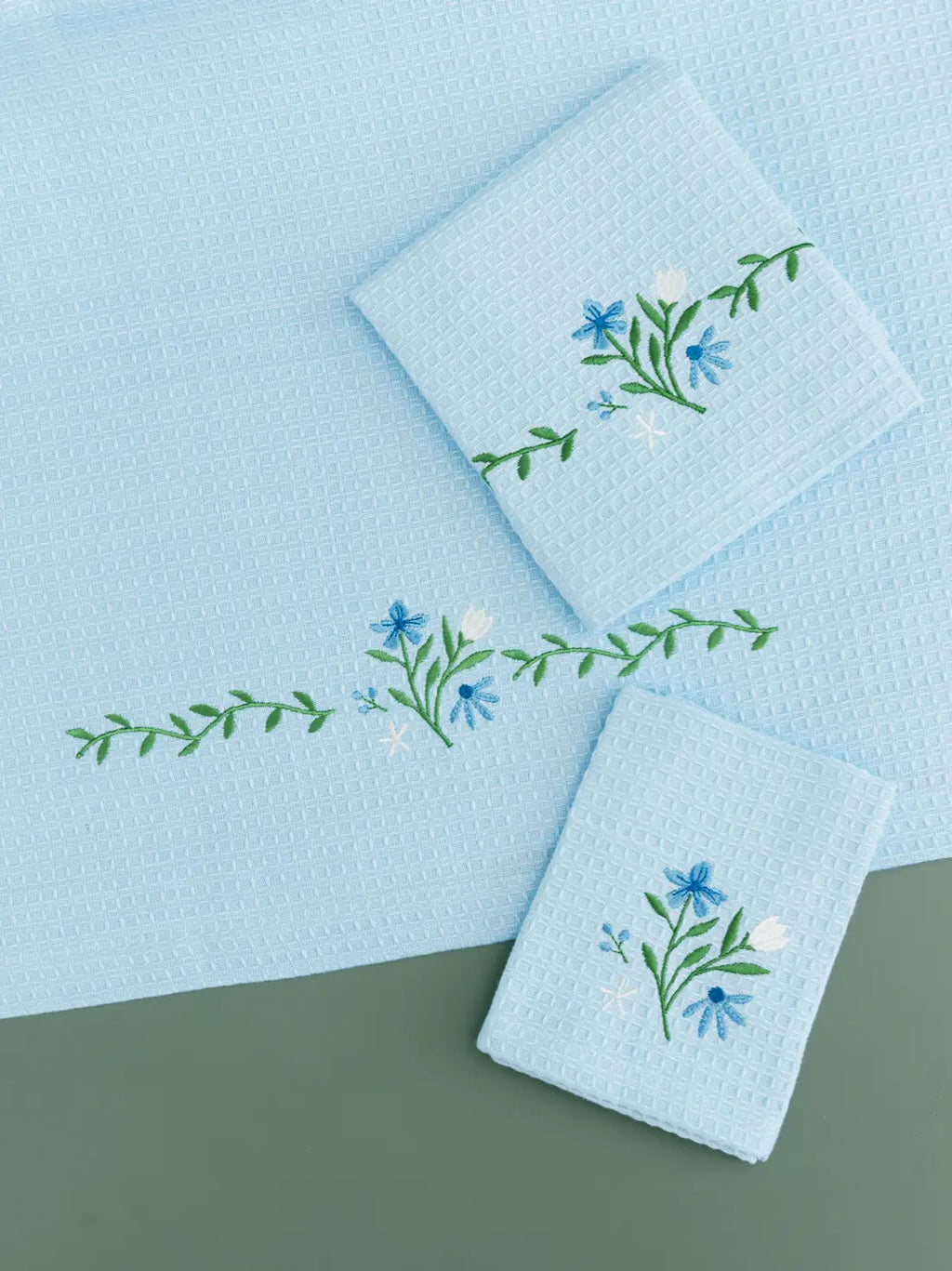 Pale blue waffle bath, hand and face towels with blue and white floral embroidery