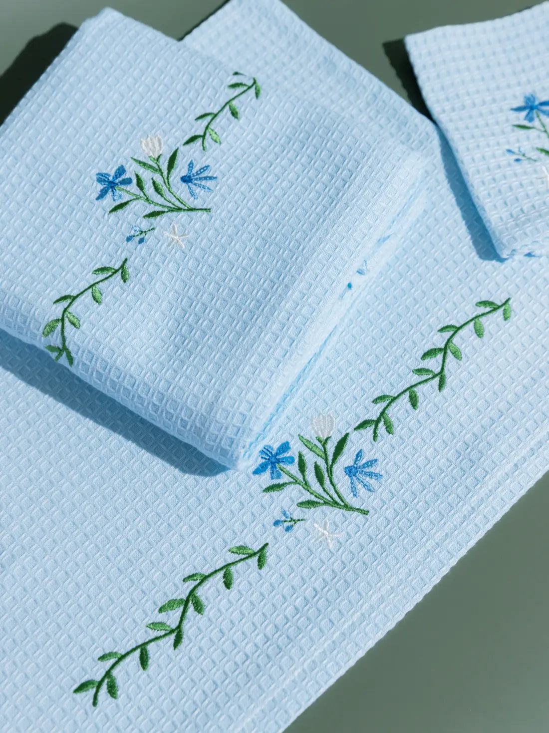 Close-up of blue and white floral embroidery on pale blue waffle towels