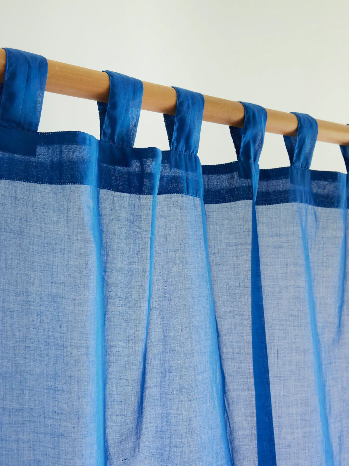 Close-up of fabric hanging loops on a blue sheer curtain