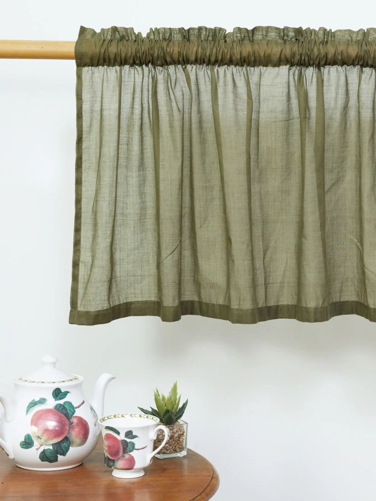 Olive green sheer cotton curtain with gathered rod pocket and darker border