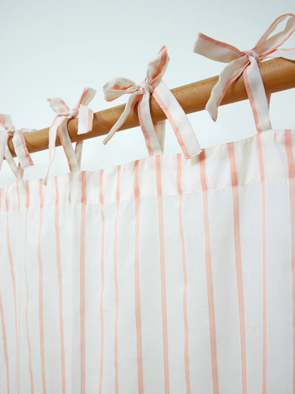 Close-up of fabric tie-top bows on a peach striped sheer curtain