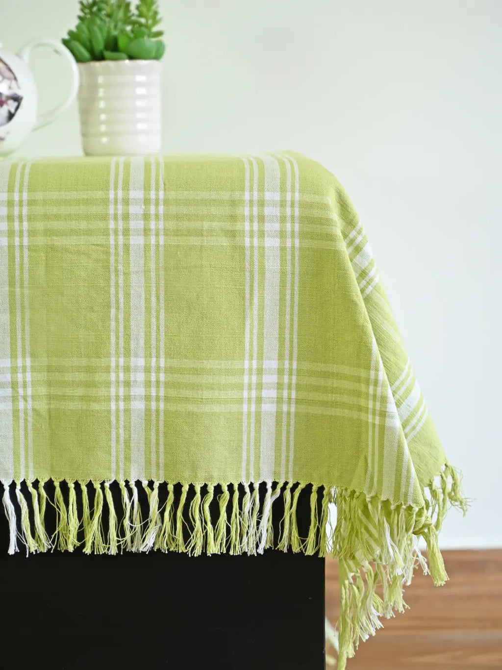 Close-up of the white plaid pattern and knotted fringe on a light green tablecloth