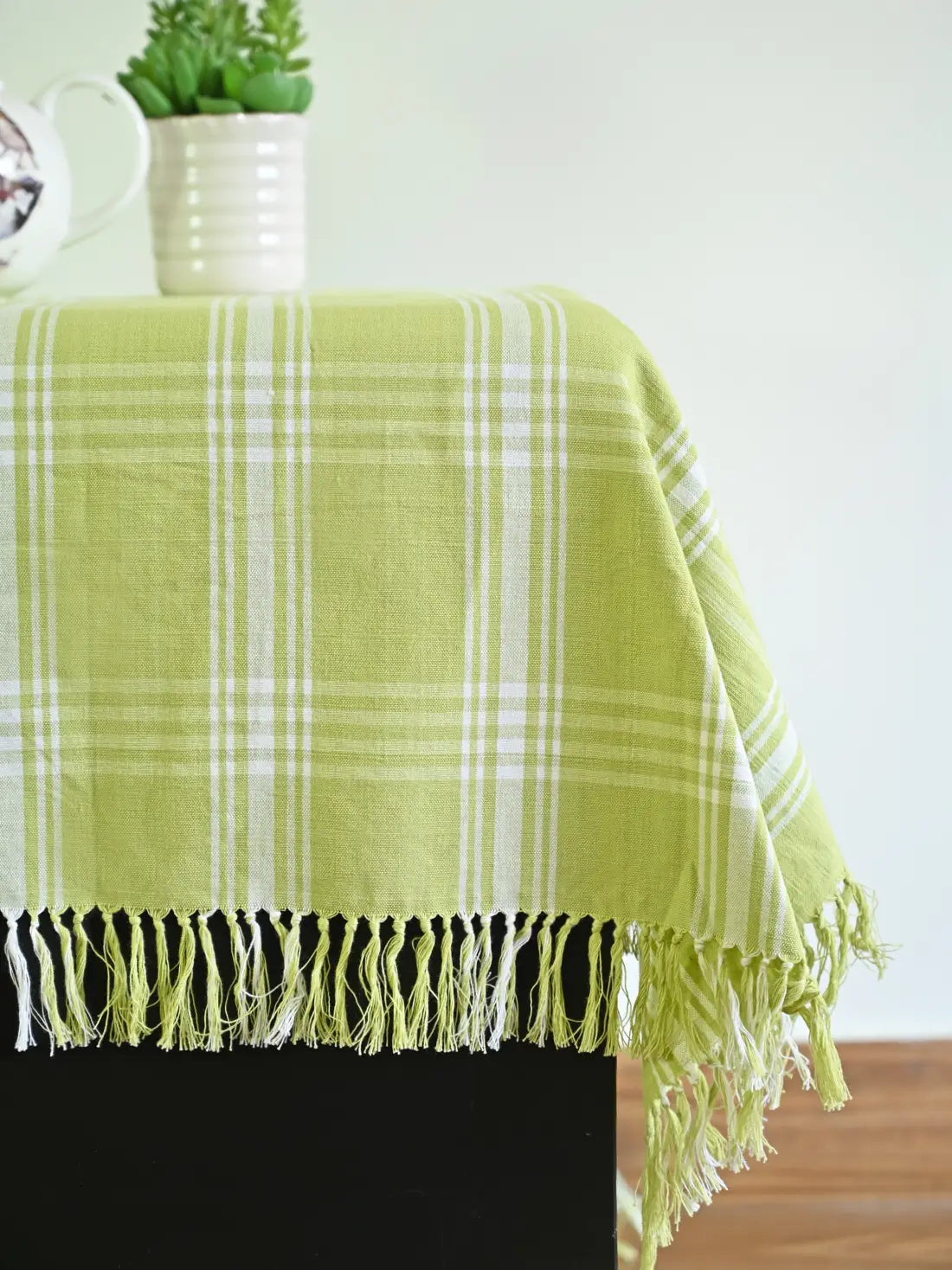 Close-up of the white plaid pattern and knotted fringe on a light green tablecloth