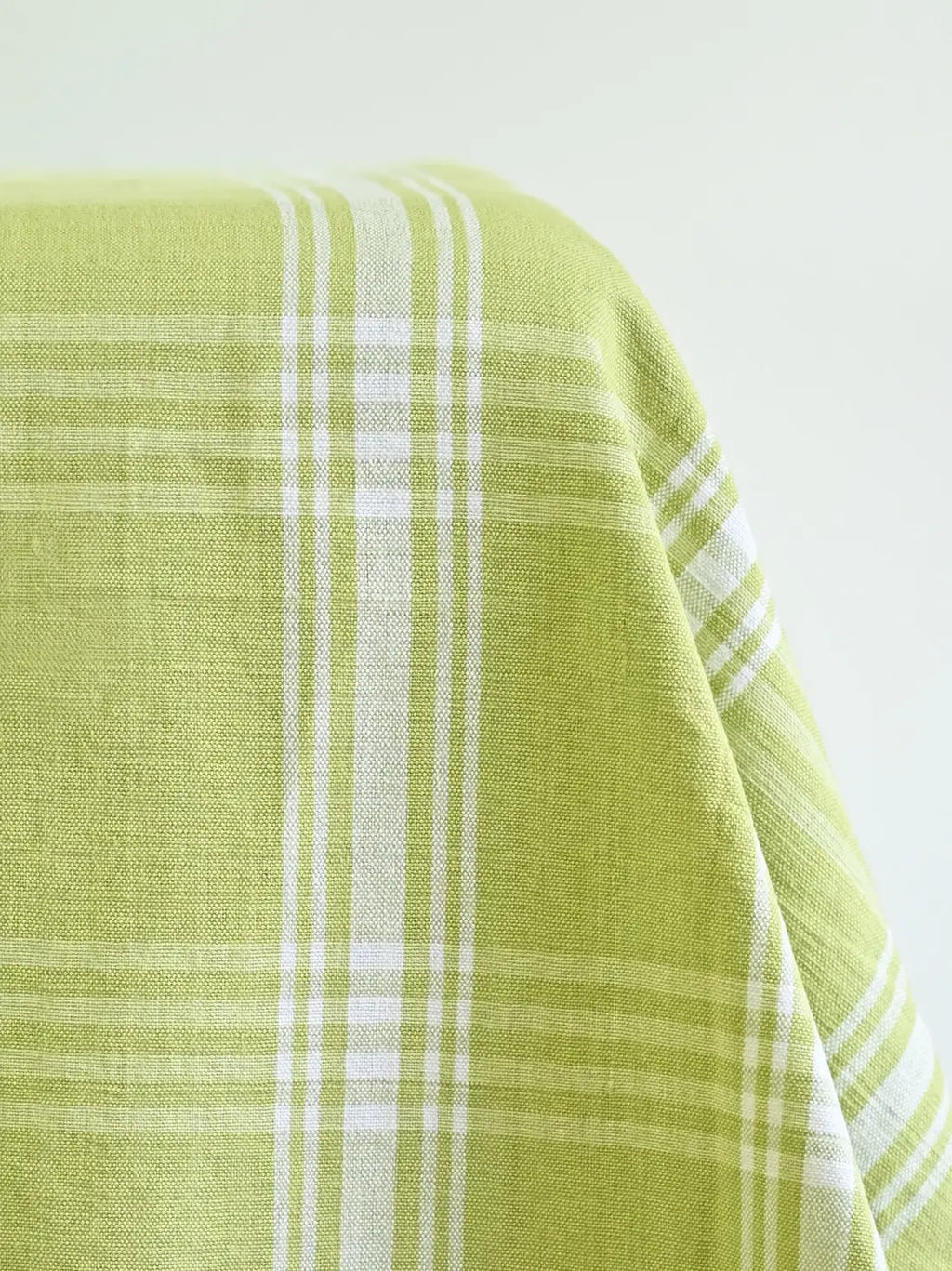 Close-up of light green woven tablecloth fabric with white plaid stripes