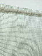 Close-up of the gathered rod pocket and green grid pattern on a white sheer curtain