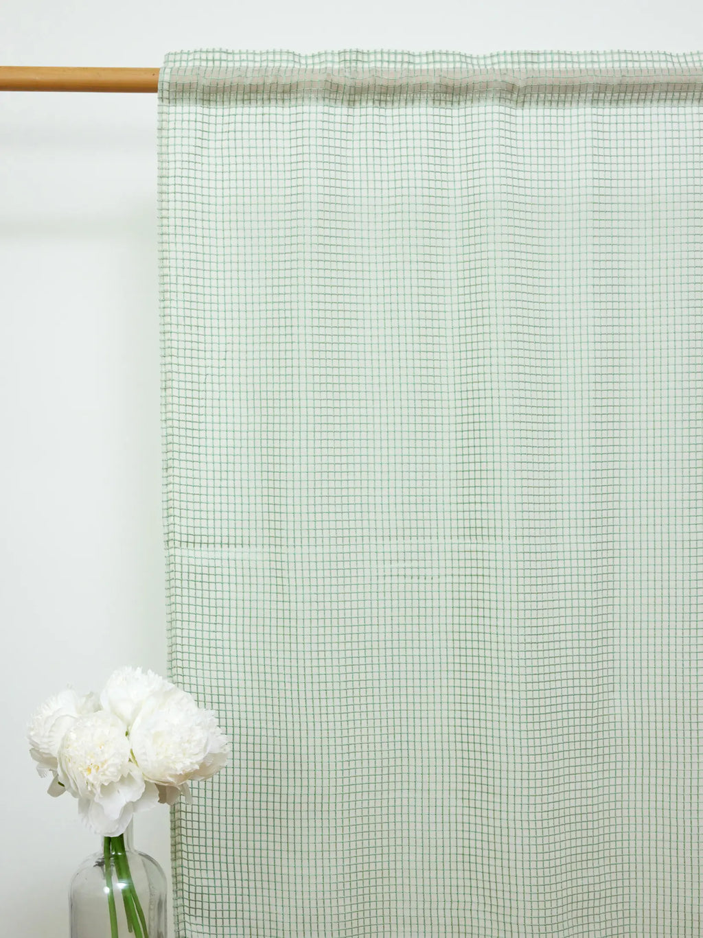 Full-length white sheer curtain with a fine green check pattern on a wooden rod