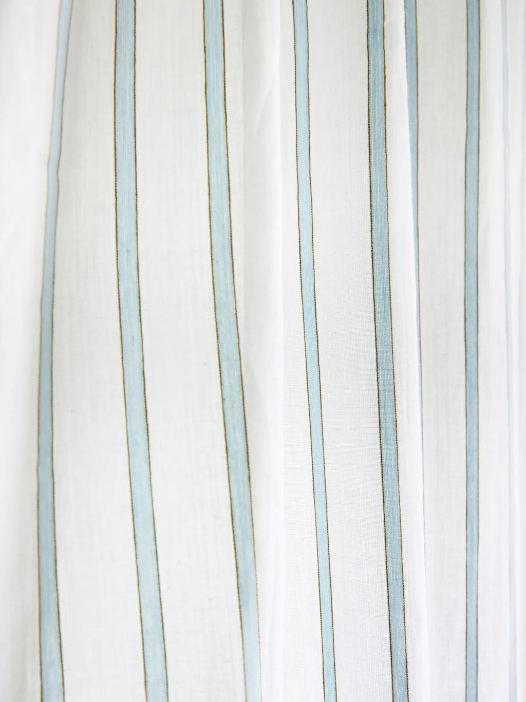 Close-up of narrow powder blue stripes on white sheer curtain fabric