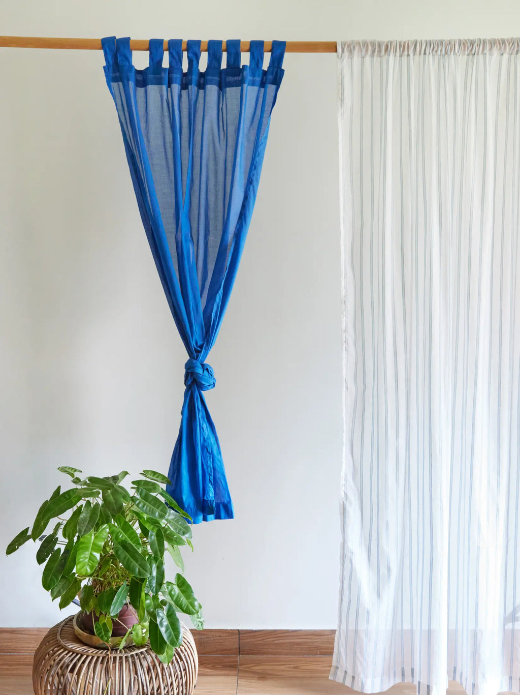 Powder blue striped white sheer curtain beside a tied blue tab-top curtain