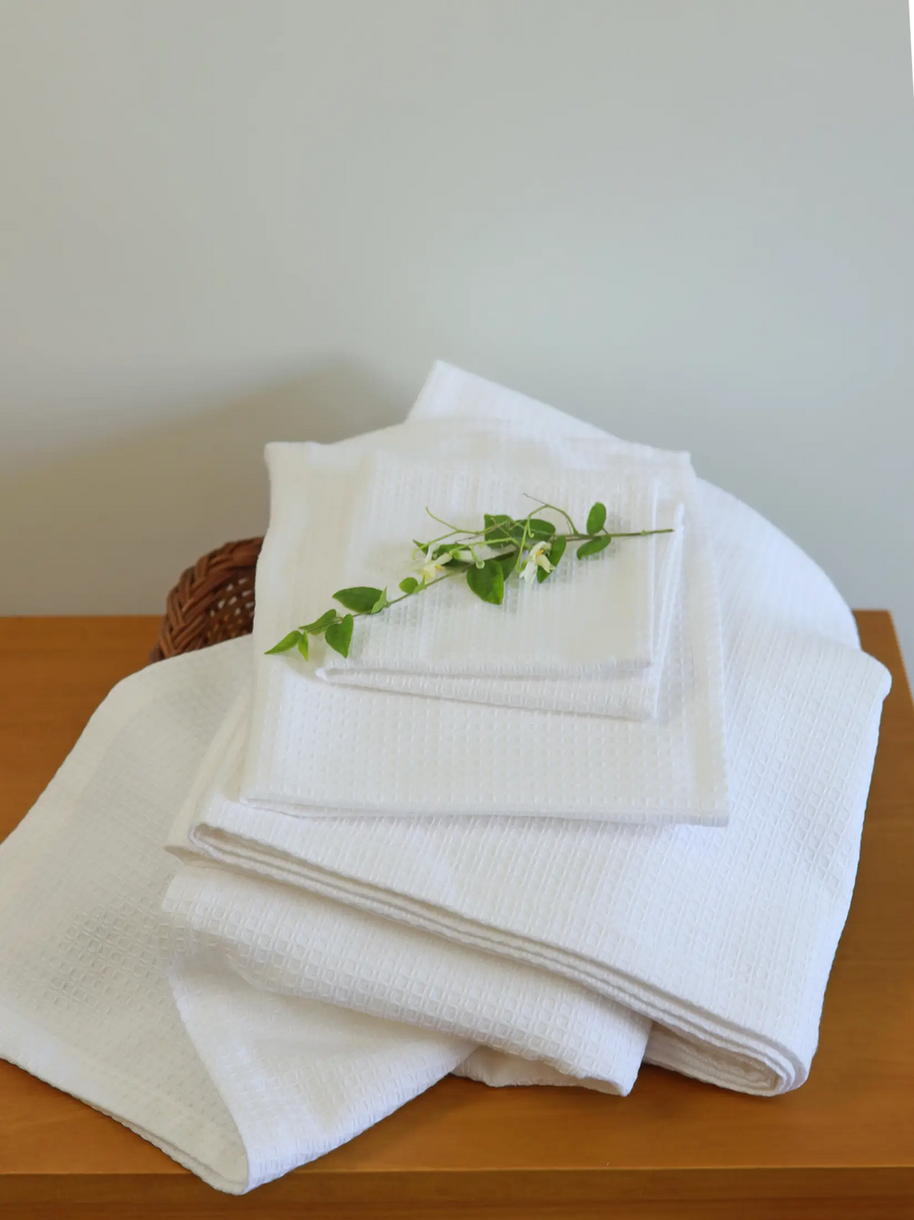 White waffle bath, hand and face towels stacked on a wooden table