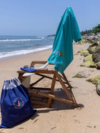 Teal blue tiger-embroidered waffle towel draped over a beach chair beside a navy drawstring bag