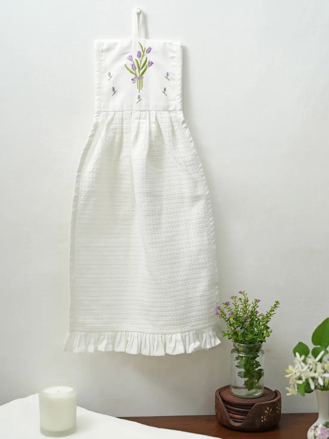 White hanging waffle hand towel with purple tulip embroidery and a ruffled hem