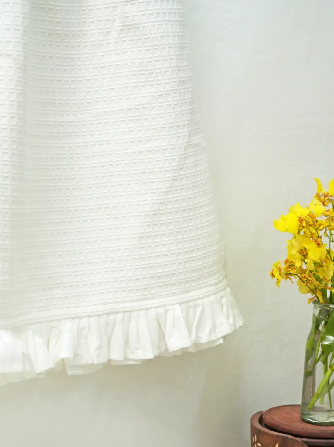 Close-up of the white ruffled hem and waffle weave on a hanging hand towel