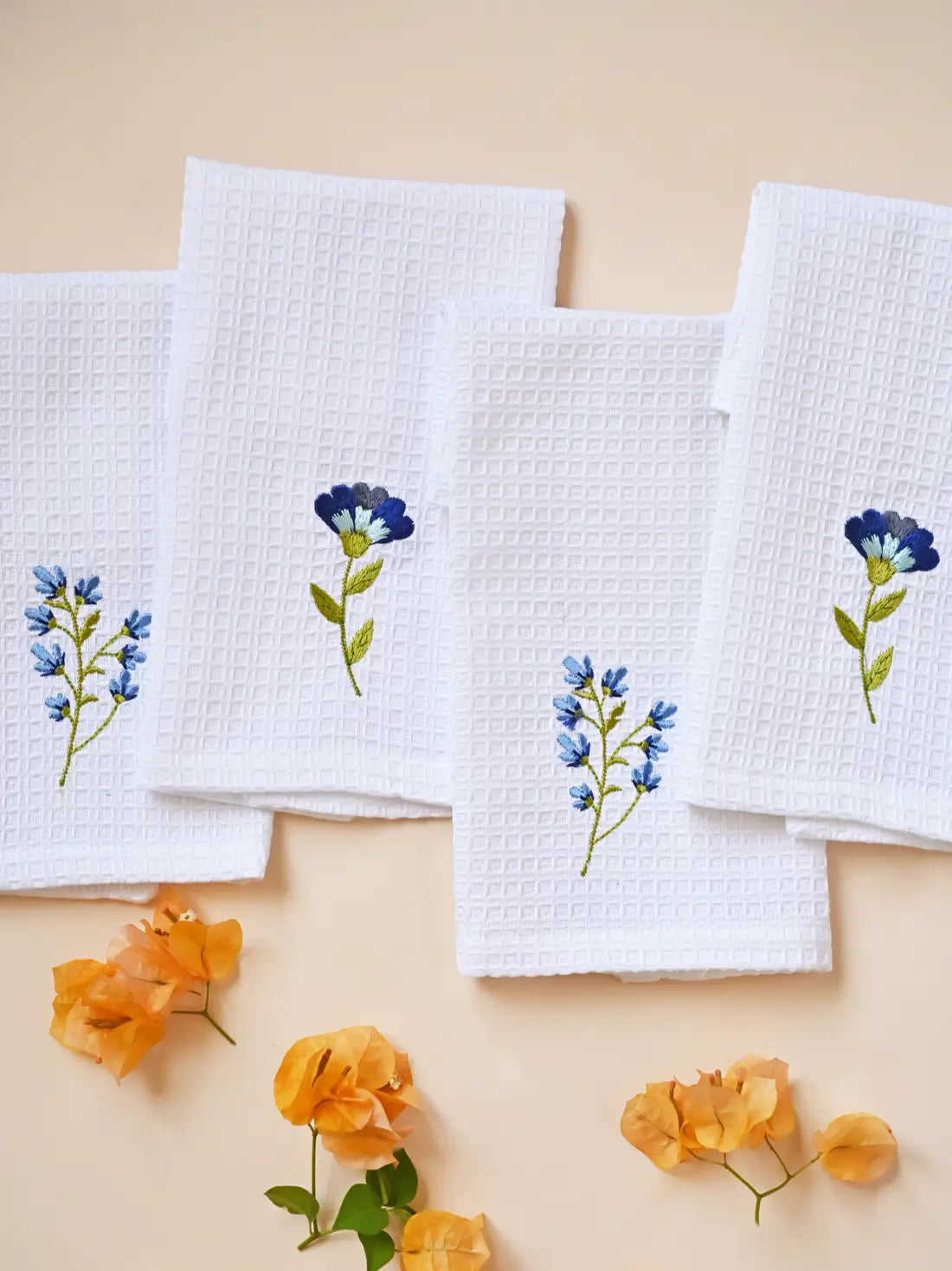 Set of four white waffle face towels with alternating blue floral embroidery