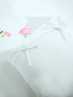 Close-up of white pillowcases with fabric bows and pink poppy embroidery